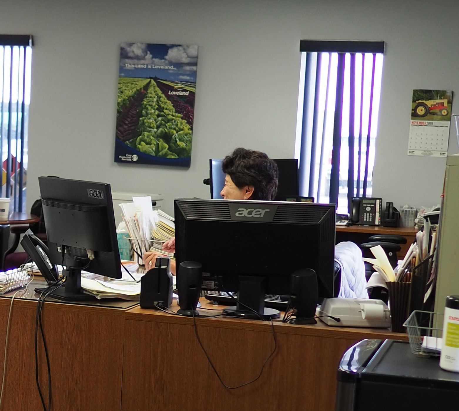 A branch administrator at a desk surrounded by paperwork and phones — the “tool” our app was actually competing with.