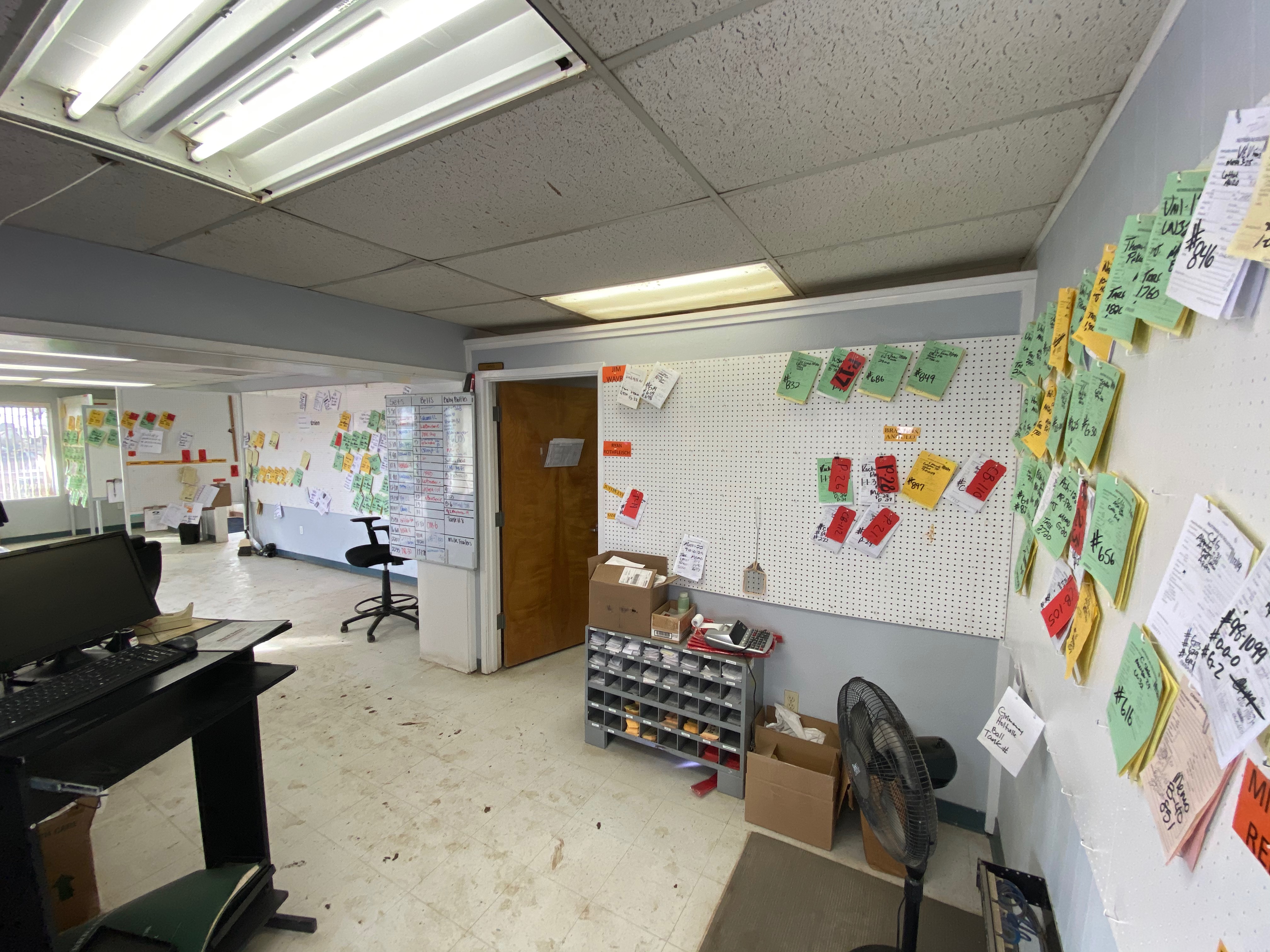 A facility’s order wall: printed orders and sticky notes pinned to a peg board, tracking dozens of in-progress orders through fulfillment.