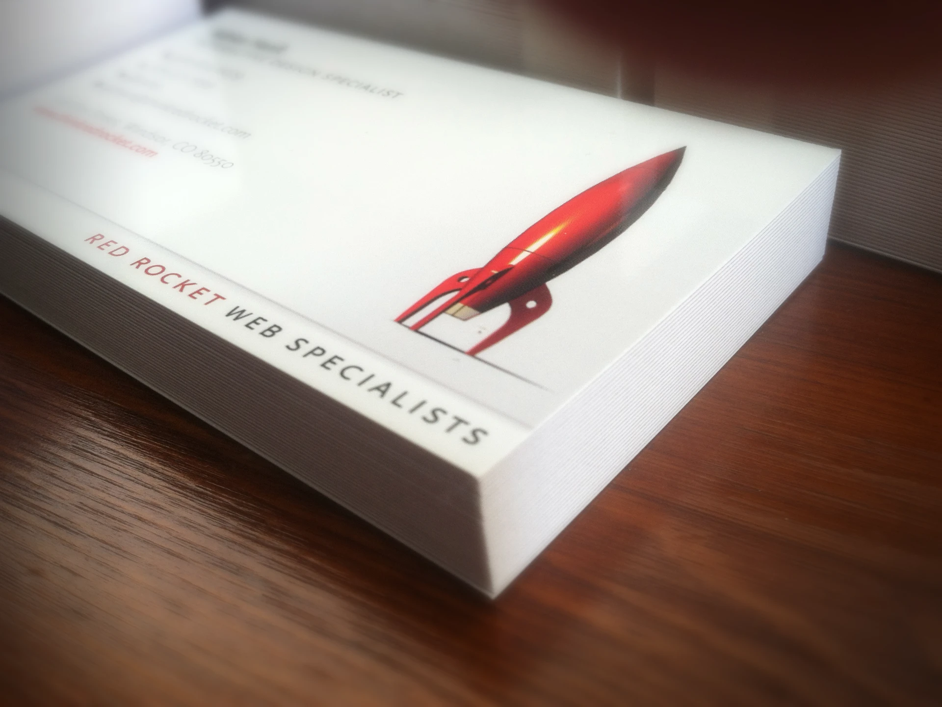 A stack of Red Rocket business cards on a desk, the rocket icon and wordmark printed clean on white.
